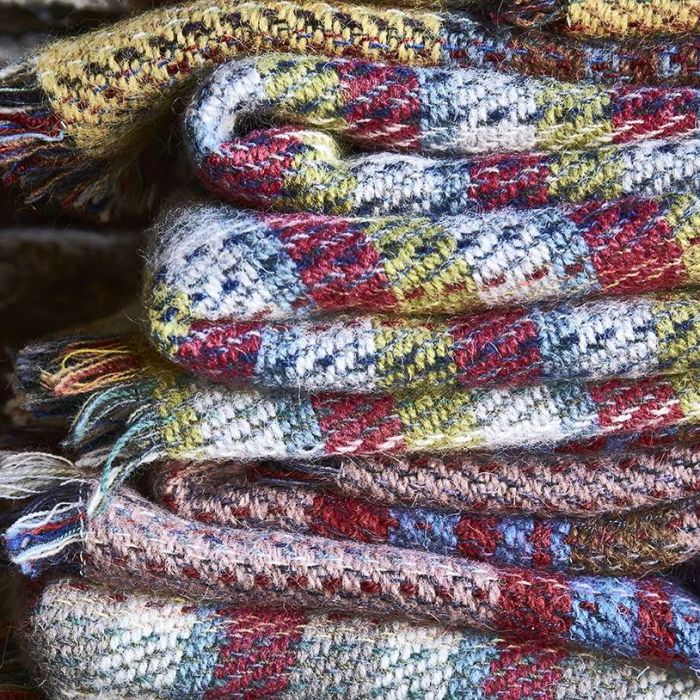 Close up view of stacked recycled rugs folded up showing the multi colour options they come in.
