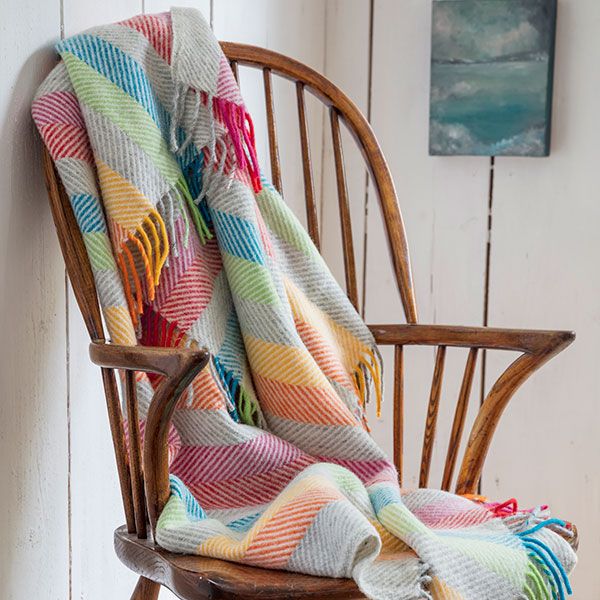 Multicolour Fishbone Throw hung over wooden arm chair to show product in situ.