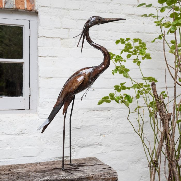 Metal heron sculpture facing to the right in a garden to show product in situ.