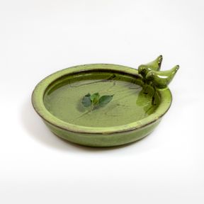 Green round bird bath on a plain grey background. The bird bath features two ceramic birds perched on the side of a bowl filled with water.