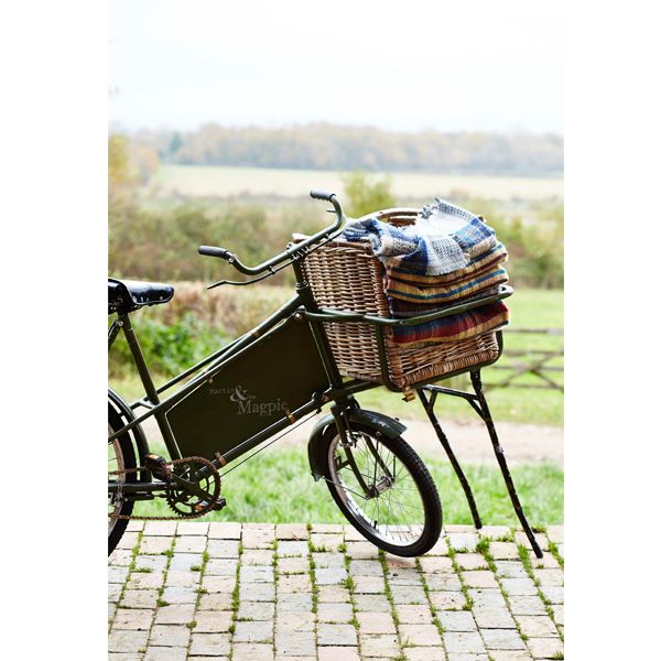 Several of the recycled rugs folded up inside a basket on a bike which is stationary. 