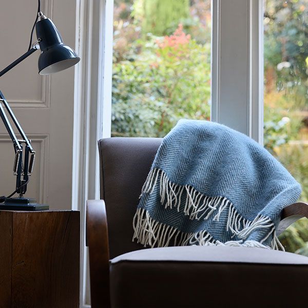 Petrol Blue Herringbone Wool Throw folded up over armchair to show product in situ.