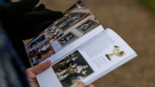 National Trust Guidebook - Visitors looking inside a guidebook, while visiting a place in our care.