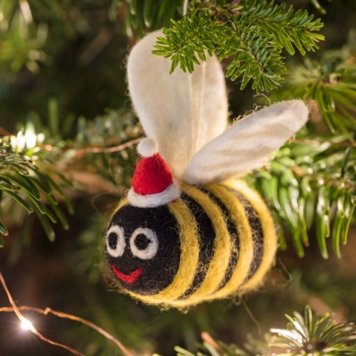 National Trust Felt Santa Bee, part of the National Trust's Christmas decorations range. Image shows felted bee with red santa hat, hanging from a Christmas tree. Browse the National Trust range for gifts, homeware and more inspired by National Trust places.