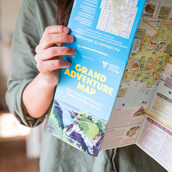 National Trust Grand Adventure Map. Image shows map including every place in National Trust and National Trust for Scotland care in the UK held open by a person planning their next trip.