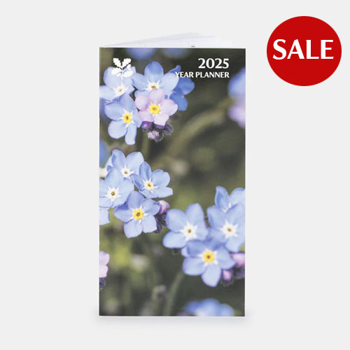 National Trust 2025 Year Planner - image shows rectangular diary with a photograph of forget me nots on the front on a plain grey background, with a red sale icon in the top right corner.