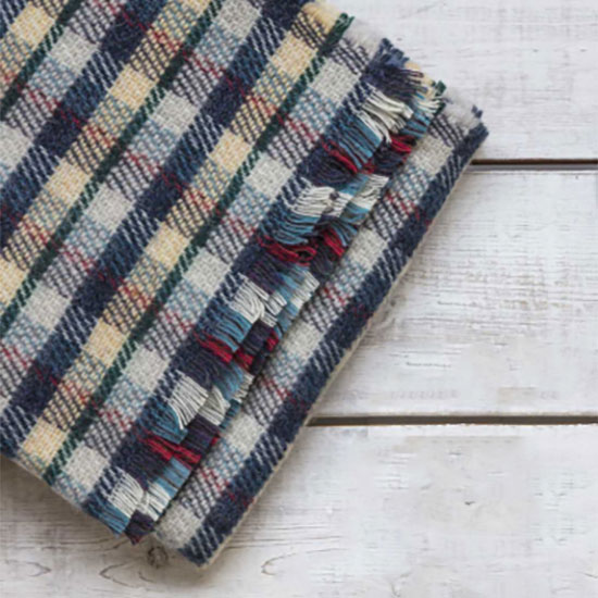 Recycled Rug - image shows outdoor blanket in blue check colourway folded up on a decking.