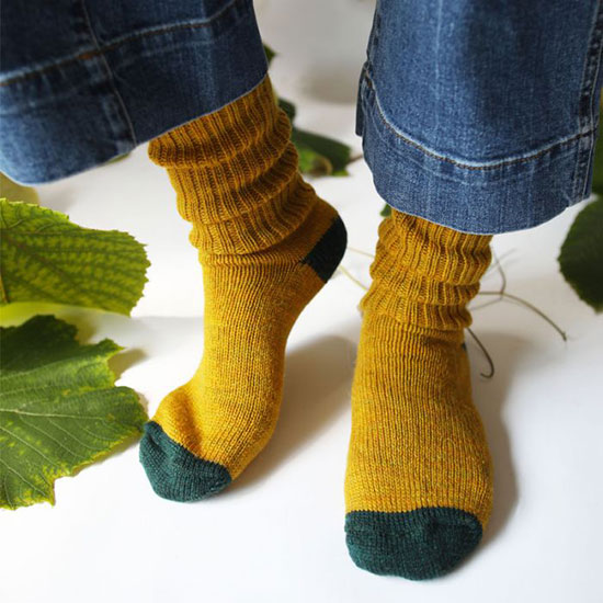 Croft Wool Socks, Green. Image shows wool socks in dark green with contrast mustard toe and heel worn by model in a studio setting.