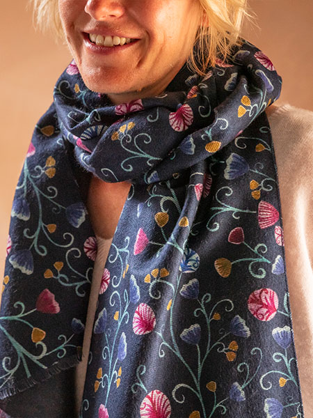 Fashion accessories - image shows Floral Scarf from the new Autumn Winter collection worn by a model in a cosy interior setting.