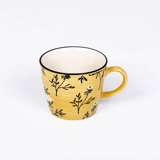 Cow Parsley Mustard Mug (£8.00), from the National Trust's spring homeware range, full of great ideas for thoughtful Easter gifts. Image shows yellow ceramic mug, decorated with black and white flower motifs, on a plain grey background.