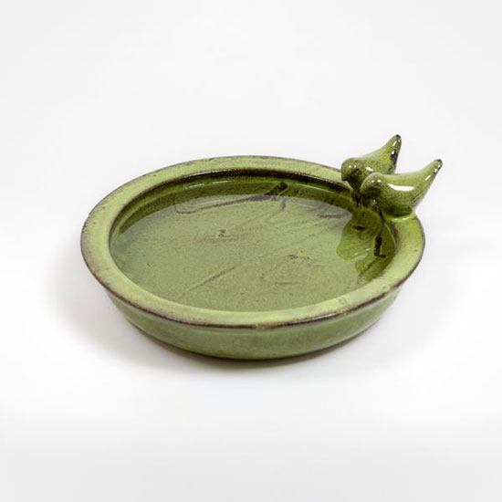 Terracotta Bird Bath - Green (£25.00), from the bird, wildlife and garden care range. Image shows green bird bath, filled with water, on a grey background. Bird bath finished with glaze and two bird motifs on edge - browse the National Trust shop for bird and wildlife care that helps look after nature.