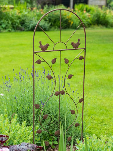 Plant supports & trellis - browse the National Trust shop for garden furniture designed with nature in mind. This image shows the Bird Leaf Trellis, finished with a brown patina, in a garden with foliage.