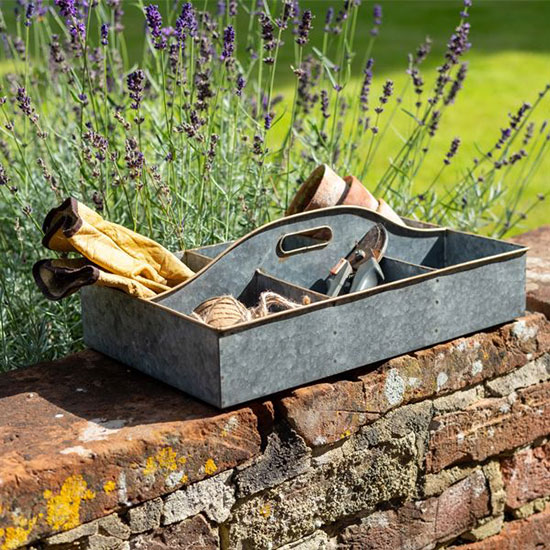 National Trust Galvanised Tray with Handle (£32.00). Image shows metal organisation tray, with galvanised finish, on a garden wall filled with gardening tools. Browse our garden range for shears, gardening gloves and outdoor accessories - every purchase helps look after the places in our care for everyone, for ever.