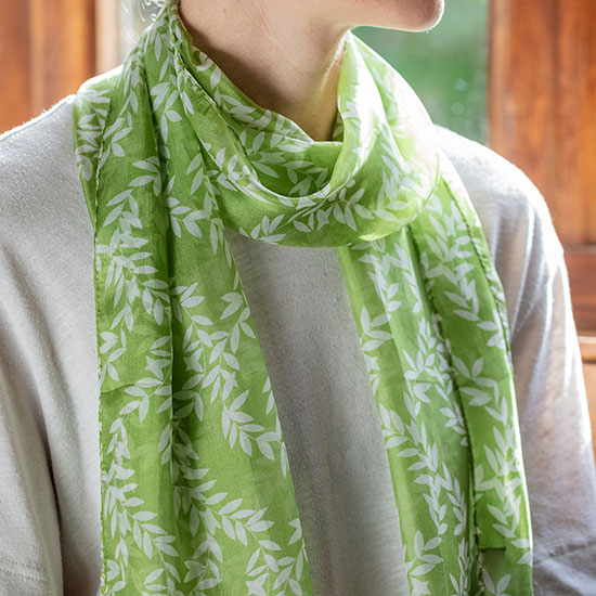 Green Vines Silk Scarf - £22.00, from the National Trust's new fashion accessories range. Made from 100% organic silk, this light green coloured scarf is decorated with a repeating vines pattern, worn by a model. Every purchase helps care for National Trust sites, 365 days a year.