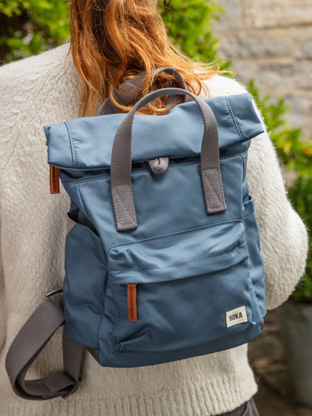 Outdoor accessories. Image shows model wearing ROKA rucksack in the shade Airforce whilst walking and exploring outside.