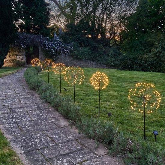 Solar Dandelion Outdoor Light (£25.00). Image shows several solar dandelion lights lit up at dusk, dotted along a garden path.