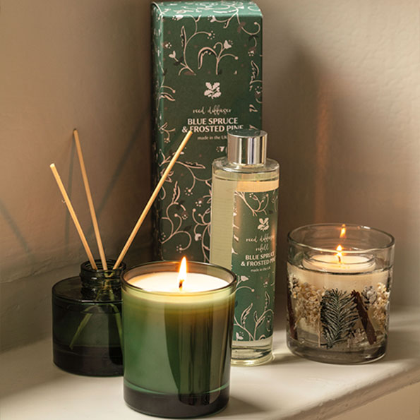 Blue spruce is back - image shows the Blue Spruce home fragrance range arranged on a windowsill, with the reed diffuser and boxed candle on display with their gift packaging inspired by Tyntesfield. 