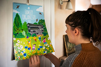 Calendars and diaries - image shows a person look at their Family Organiser in a kitchen setting. 