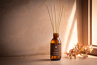 Home fragrance - image shows the Coffee and Bergamot Reed Diffuser on a windowsill, with a soft light shining through the window and illuminating the retro, vintage inspired glass bottle.