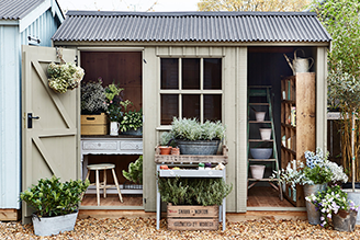 Sheds - image shows a shed from the Crane x National Trust collection, with doors open and garden tools arrayed inside.