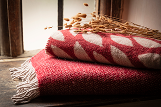 Throws & blankets - image shows the Jacquard Leaves Throw paired with the Illusion Red Throw on a windowsill, with pampas grass adding a natural touch to the home decor.